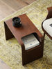 Picture of Walnut Side Table next to  bed slotted over the seat of a sofa otis side table